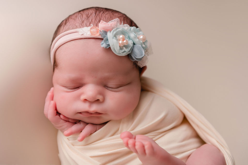 little newborn girl in a flower headband wrapped in neutral colors Connecticut Baby Stores
