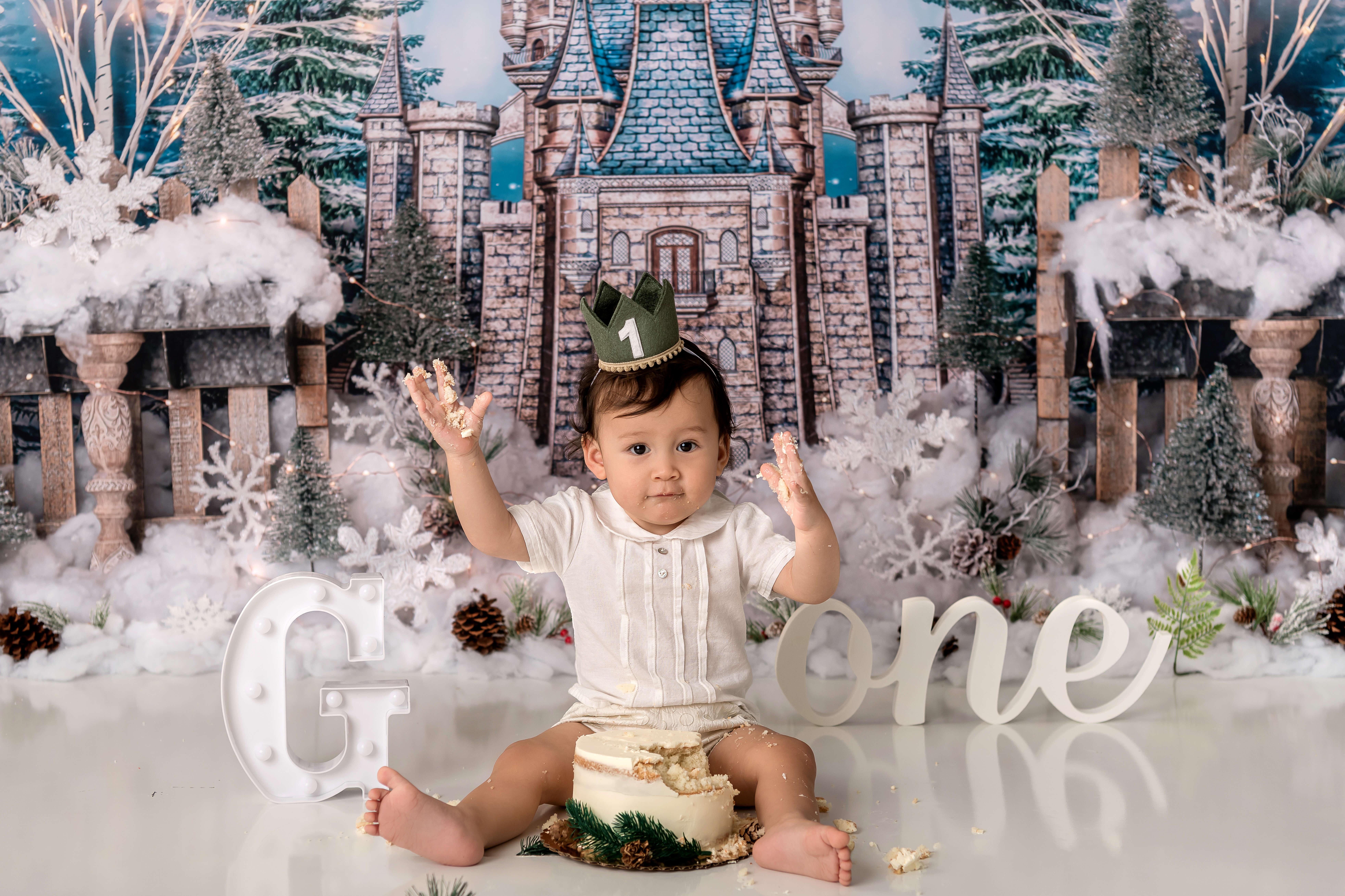 Baby boy holding his hands up in the air for his cake smash photo shoot